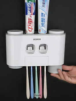Automātiskā vannas istaba zobu pastai, dozators, zobu pasta squeezer, kas piestiprināts pie sienas turot zobu suka